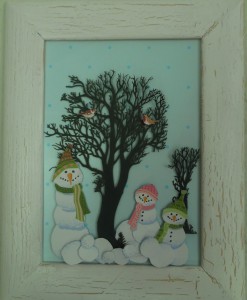 Snemænd og snebolde i læ under et træ, lavet af papir og indrammet
