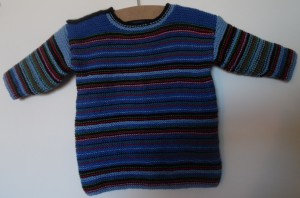 Lækker retstrikket trøje i striber med farverne sort, blå, lyseblå, rød og grøn. Blusen har skulderlukning