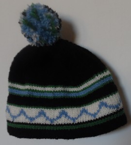 Tophue strikke i blåt, grønt, hvidt og sort garn, pompom er i de samme farver