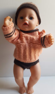 dukketøj strikket i ferskenfarvet og brunt garn, trøje med lange ærmer, korte bukser og hue